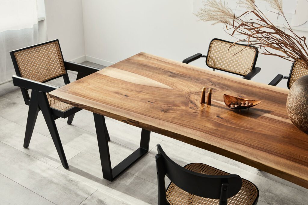 Interior design of stylish dining room interior with family wooden table, modern chairs, plate with nuts, salt and pepper shakers